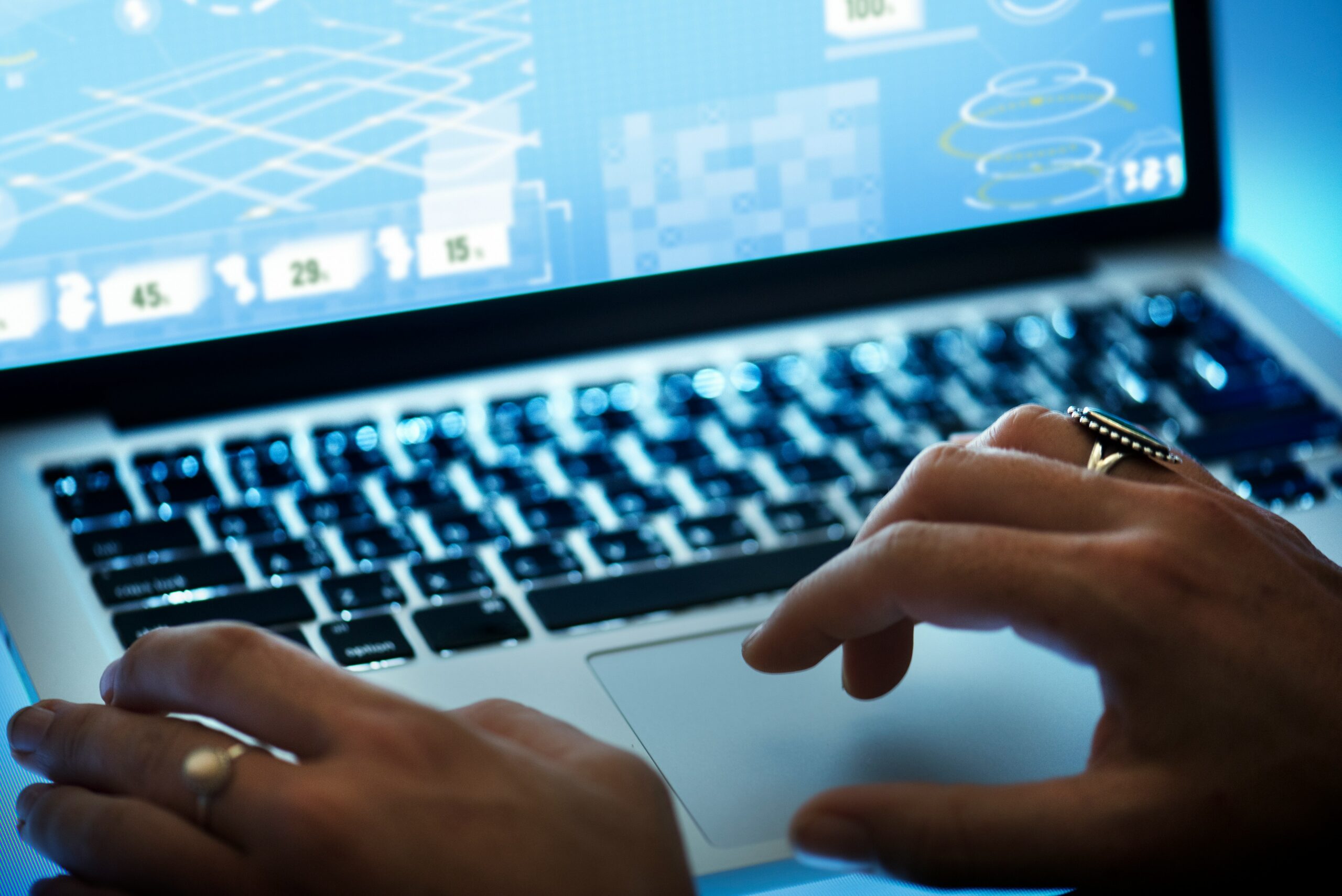 Person arbeitet an einem Laptop mit digitalen Grafiken und Datenvisualisierungen auf dem Bildschirm.
